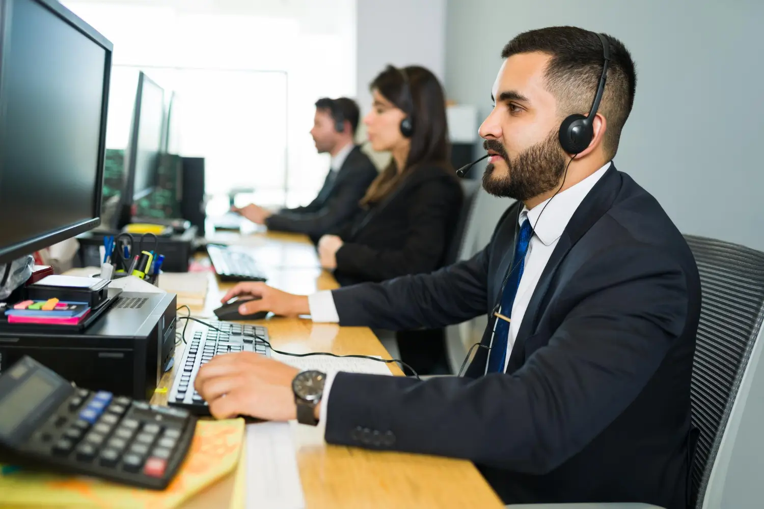 A Mr. Klin support agent wearing a headset, taking customer enquiries at a desk